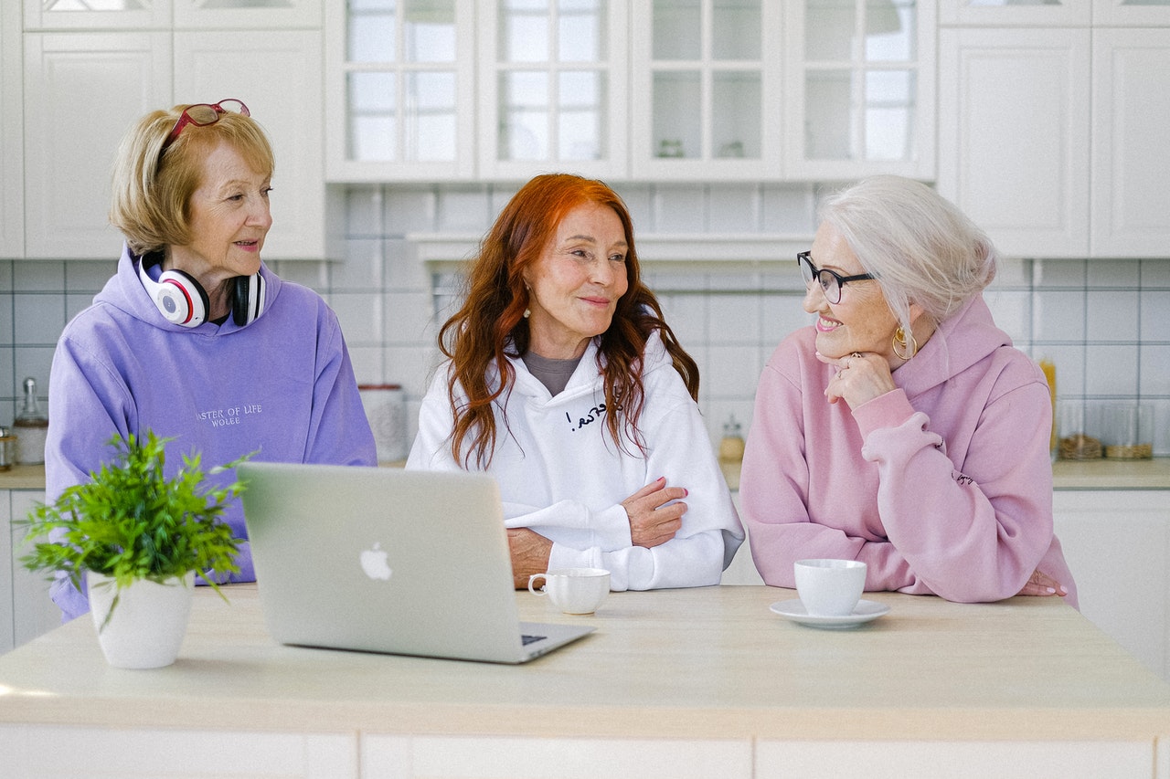 trois femmes seniors dans une cuisine assises devant un ordinateur